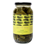 The Artisan Cheese Room jar of baby cornichons with a yellow label featuring a pickle pattern