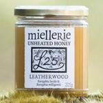 The Artisan Cheese Room Miellerie Leatherwood unheated honey in a 325g glass jar resting on a mossy forest surface.