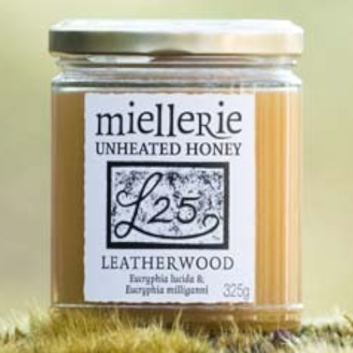 The Artisan Cheese Room Miellerie Leatherwood unheated honey in a 325g glass jar resting on a mossy forest surface.