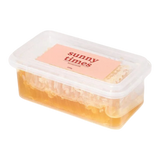 The Artisan Cheese Room Sunny Times raw honeycomb in a clear plastic container with a pink label on a white background